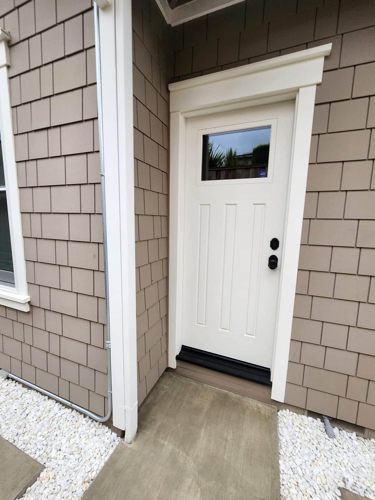 White entry door and trim against freshly painted shingle siding