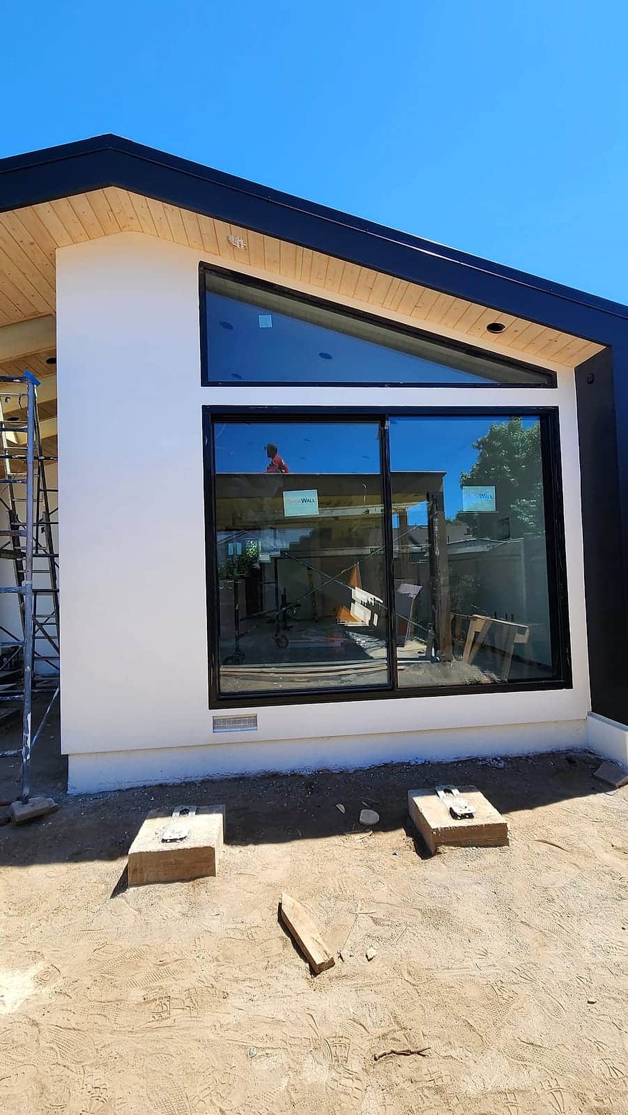 Modern farmhouse gable with black trim and a full-height corner window after painting