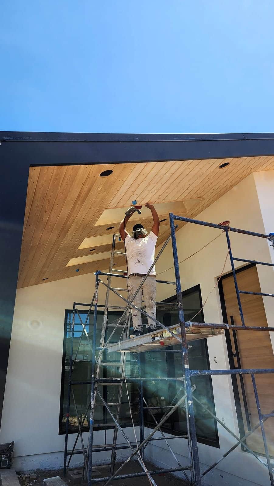 Scaffold work finishing the wood porch ceiling of a modern home